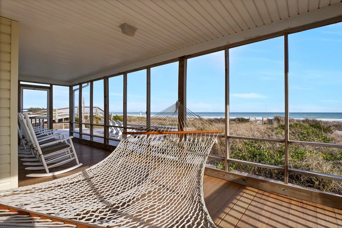This image features a tranquil oceanfront setting with a hammock and rocking chairs placed on a porch or deck, overlooking the rolling waves. The vantage point emphasizes the exclusive relaxation spots—perfect for lounging, reading, or simply soaking in the panoramic seaside views.