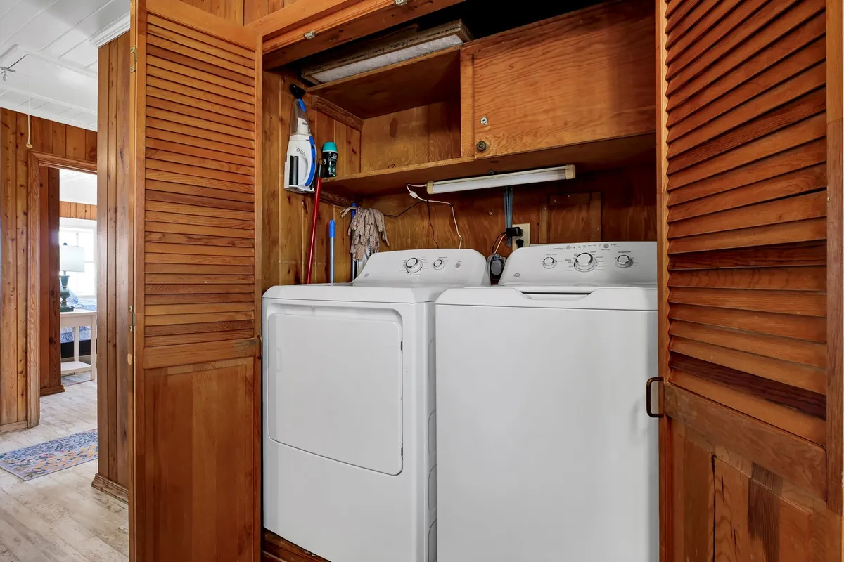 A practical laundry nook with a washer and dryer neatly installed beneath wooden cabinetry. The area is organized and bright, presenting a convenient space for handling laundry tasks during a vacation stay.