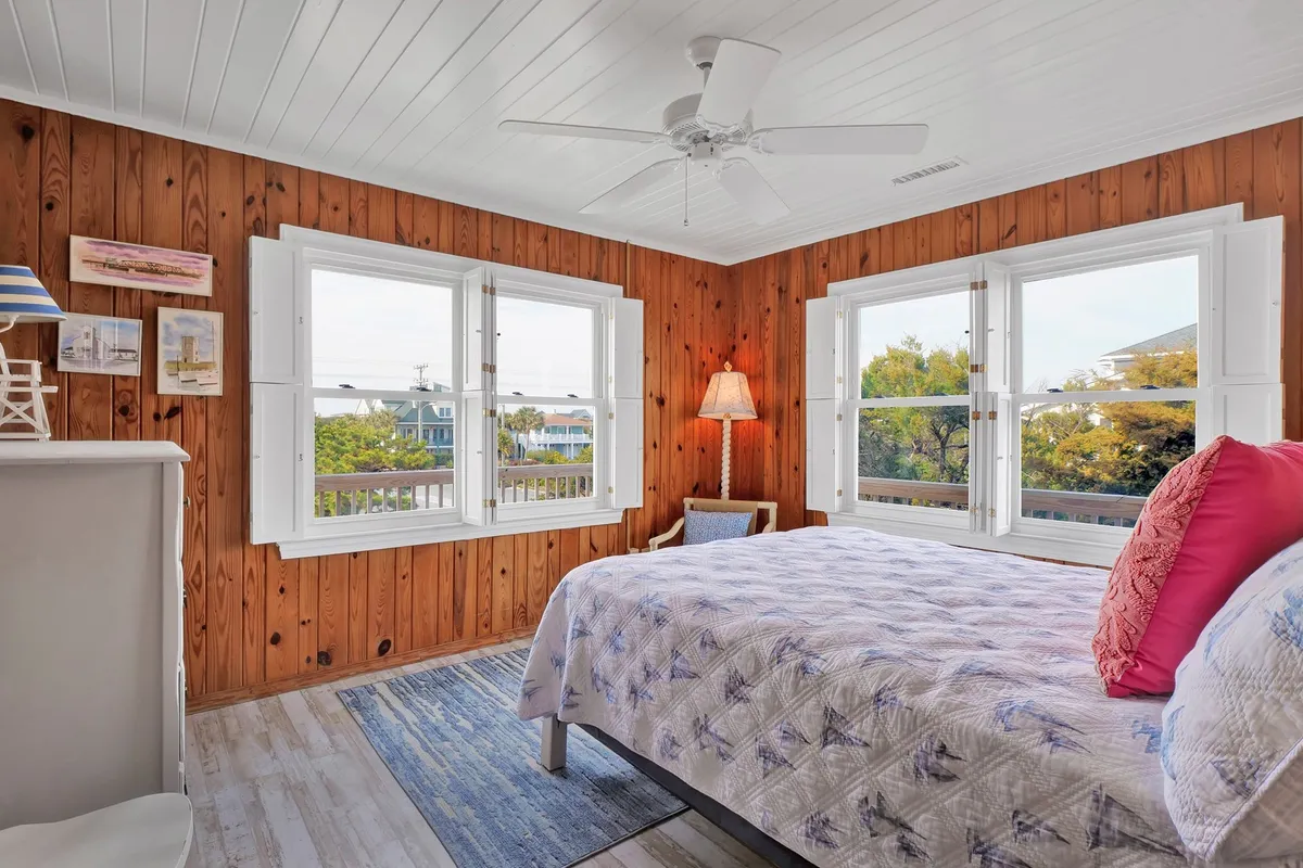 A tranquil bedroom interior with a bed positioned near large windows that offer views of the surrounding landscape. Natural sunlight streams in, illuminating the cozy decor and inviting a sense of peaceful relaxation and connection to the outdoors.